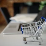 Fermeture de Rakuten : photo d’illustration d’un petit chariot de courses devant un ordinateur portable.