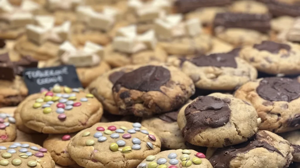 Biscuits au chocolat et aux pastilles colorées exposés dans une boulangerie.