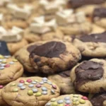 Biscuits au chocolat et aux pastilles colorées exposés dans une boulangerie.