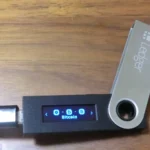 Portefeuille matériel Ledger Nano S connecté par USB, utilisé en illustration des agressions crypto.
