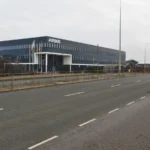 Bâtiment gris portant le nom Airbus, derrière des drapeaux et une large route à Stevenage.