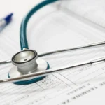 Un stéthoscope et un stylo posés sur un document médical.