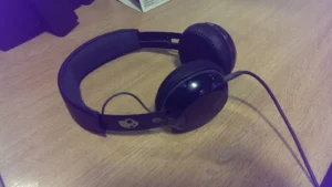 Casque audio Skullcandy noir posé sur un bureau en bois, avec son câble.