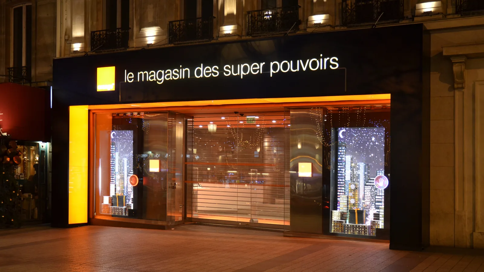 Devanture éclairée d’une boutique Orange sur les Champs-Élysées, à Paris.