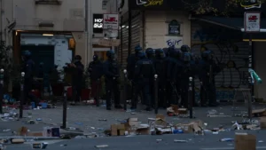 Rue de Paris jonchée de cartons et de débris devant des commerces fermés, avec des policiers en tenue anti-émeute, le 17 octobre 2026