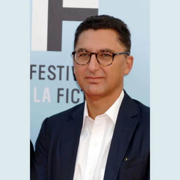 Maxime Saada, portant des lunettes, une veste sombre et une chemise blanche.