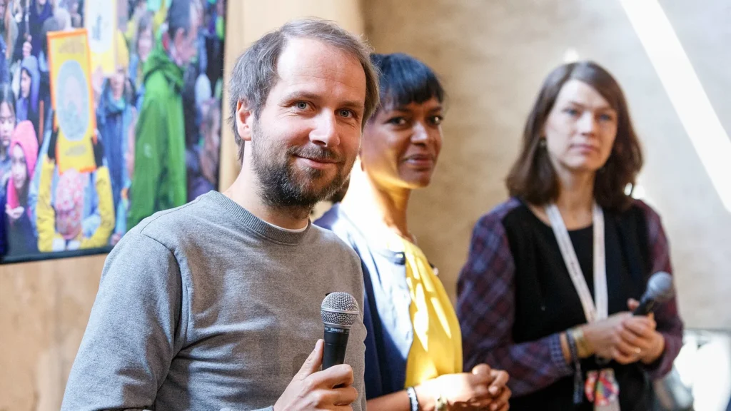 Christian Kroll, fondateur d’Ecosia, tenant un microphone au premier plan lors de re:publica.