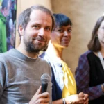 Christian Kroll, fondateur d’Ecosia, tenant un microphone au premier plan lors de re:publica.