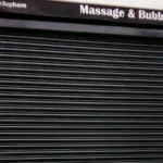Rideau métallique noir baissé devant un commerce.
