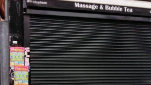 Rideau métallique noir baissé devant un commerce.