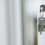 Clé dans une serrure et porte-clés en forme de maison, illustrant une donation pour un logement.