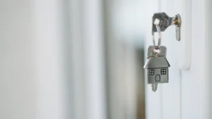 Clé dans une serrure et porte-clés en forme de maison, illustrant une donation pour un logement.