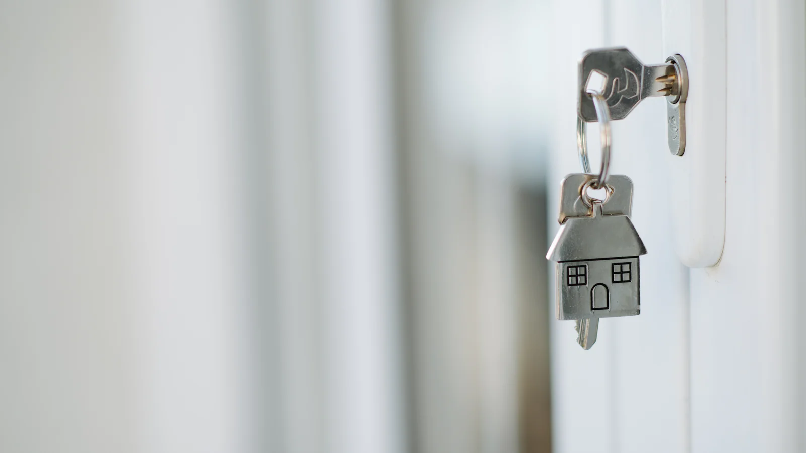 Clé dans une serrure et porte-clés en forme de maison, illustrant une donation pour un logement.