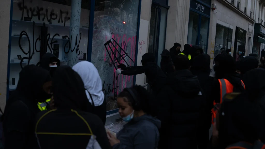 Vitrine brisée et taguée d’un commerce à Paris, avec plusieurs personnes devant, le 17 octobre 2026.