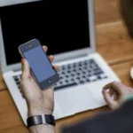 Homme utilisant un ordinateur portable et un smartphone à un bureau, photo d’illustration de l’apprentissage numérique.