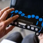 Gros plan sur des mains utilisant une plage braille portable à touches bleues.