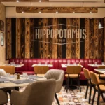 Salle du restaurant Hippopotamus Paris Montparnasse, avec banquettes rouges, fauteuils et décor en bois.