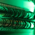 Câbles réseau raccordés à une baie informatique sous un éclairage vert.