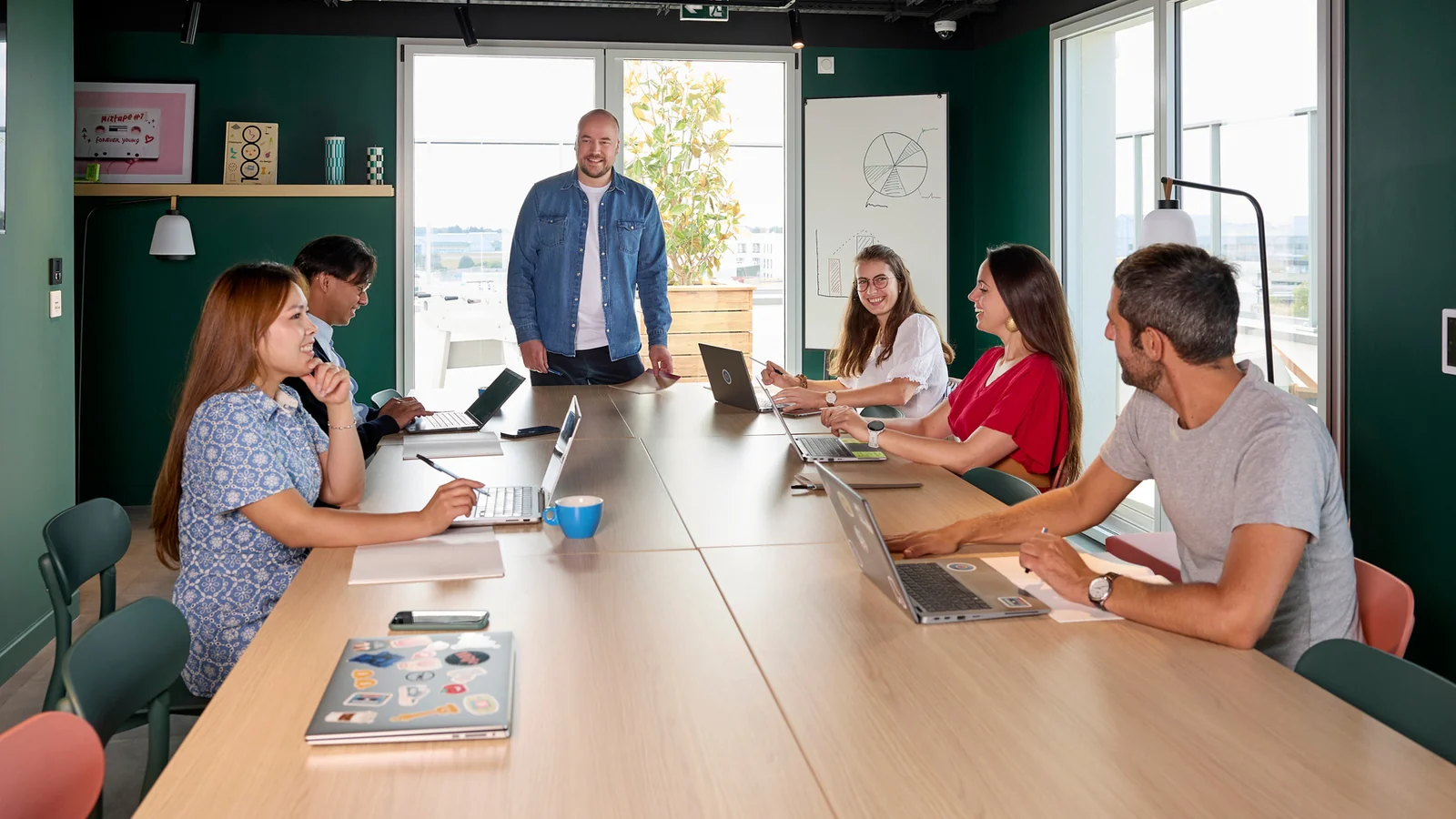 Six personnes réunies autour d’une table avec des ordinateurs portables dans un espace de coworking.