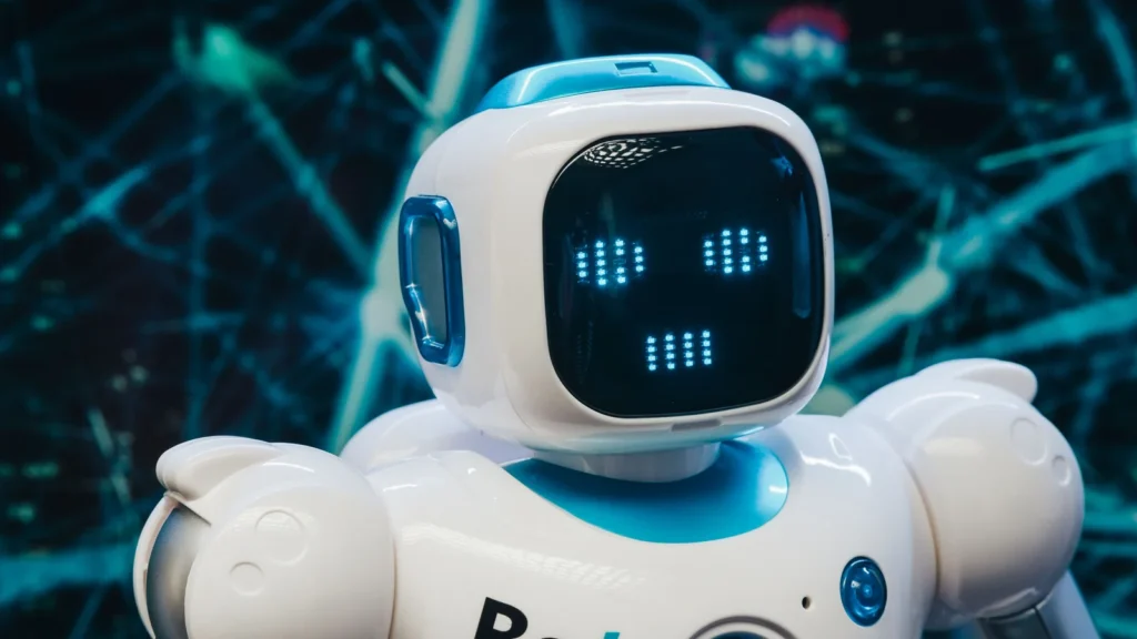 Gros plan sur un robot blanc au visage numérique lumineux dans une ambiance bleutée.