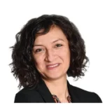 Portrait de Meryem Yilmaz, aux cheveux bouclés, en veste sombre sur fond blanc.