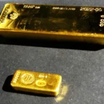 Une barre et un petit lingot d’or présentés sur un support sombre.