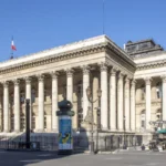 Façade à colonnes du palais Brongniart à Paris, sous un ciel bleu.