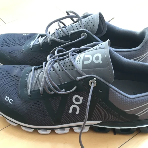 Chaussures On Running Cloudflow noires et grises, avec leur semelle à éléments creux.
