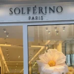 La devanture de la boutique Solférino Paris, avec sa porte ouverte et sa vitrine fleurie.