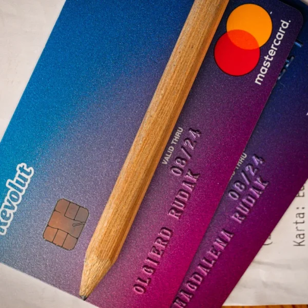 Deux cartes bancaires Revolut Visa et Mastercard posées sur un ticket, avec un crayon.