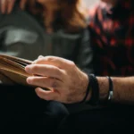 Un couple lit un livre sur un canapé, illustration de l’article sur les petites retraites.