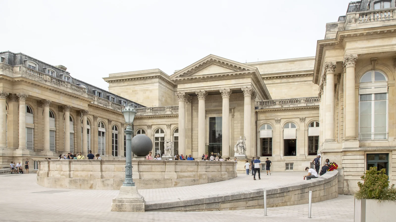 Façade du palais Bourbon et cour intérieure, avec des visiteurs devant les colonnes.