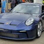 Porsche 911 S/T bleue vue de trois quarts avant, entourée de visiteurs