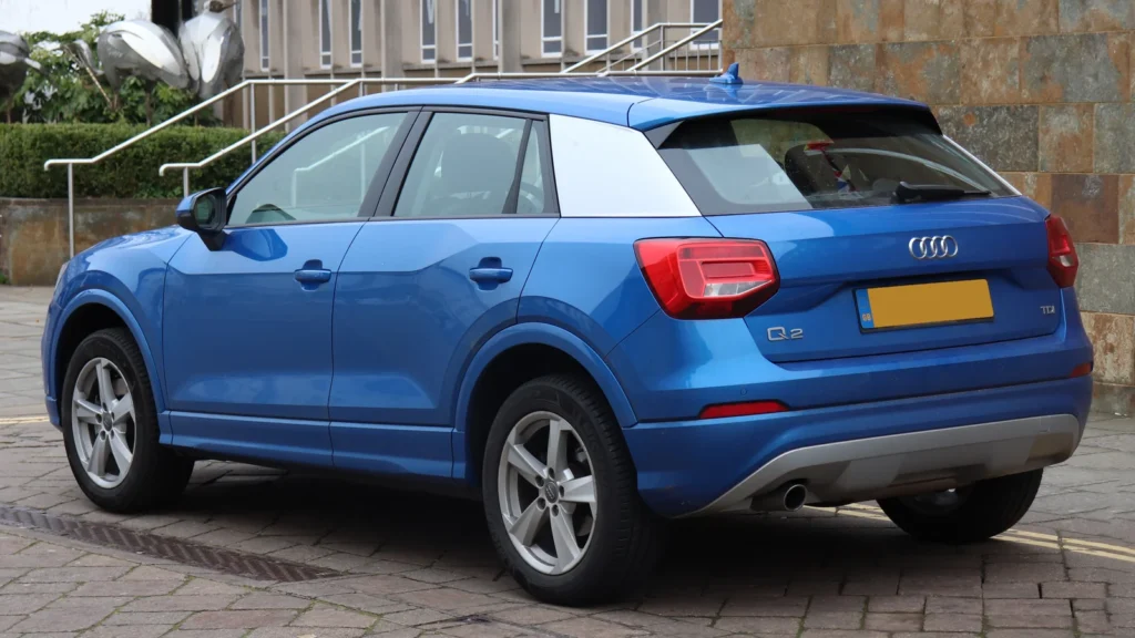 Audi Q2 bleu vu de trois quarts arrière, avec son habillage de pilier C visible.
