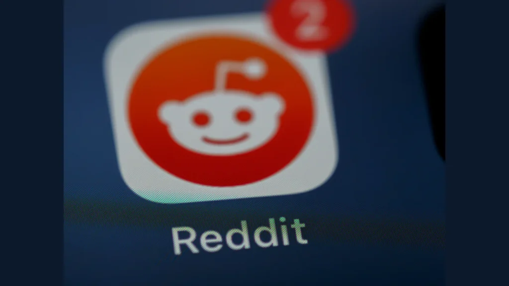 Gros plan de l’icône orange et blanche de Reddit sur un écran, avec le nom de l’application.