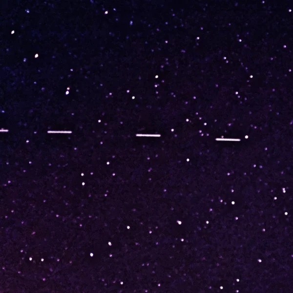 Six satellites Starlink apparaissent sous forme de courts traits lumineux alignés dans un ciel étoilé.