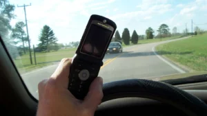 Téléphone au volant : un téléphone portable tenu en main devant le pare-brise.