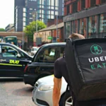Coursier portant un sac Uber Eats dans une rue de Manchester