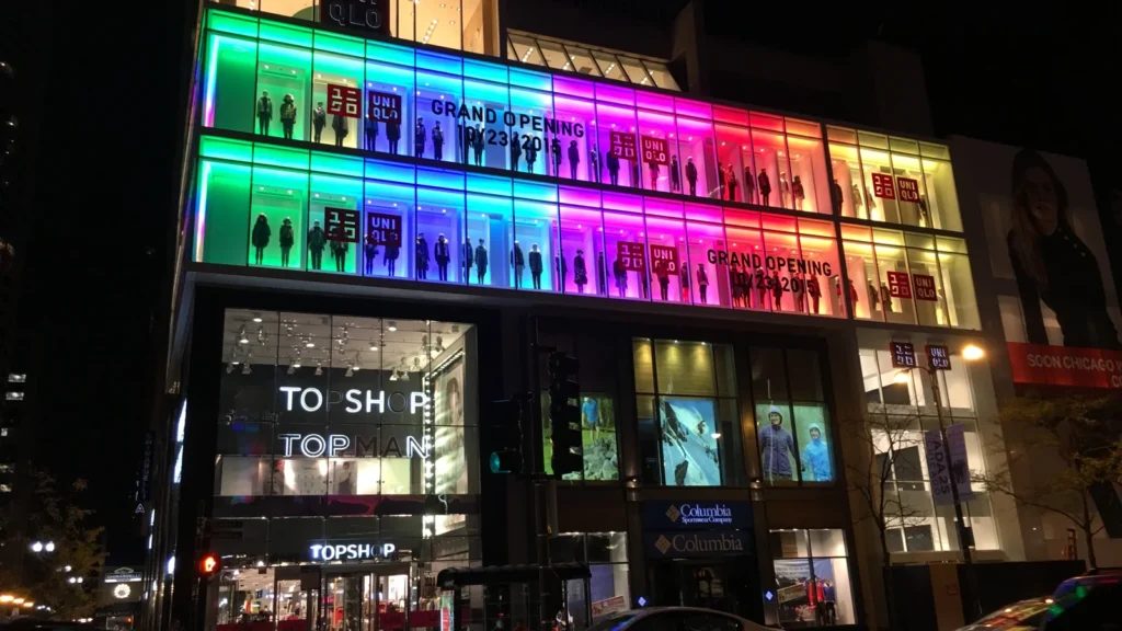 Façade vitrée du magasin Uniqlo de Chicago éclairée de nuit, avec ses enseignes rouges.