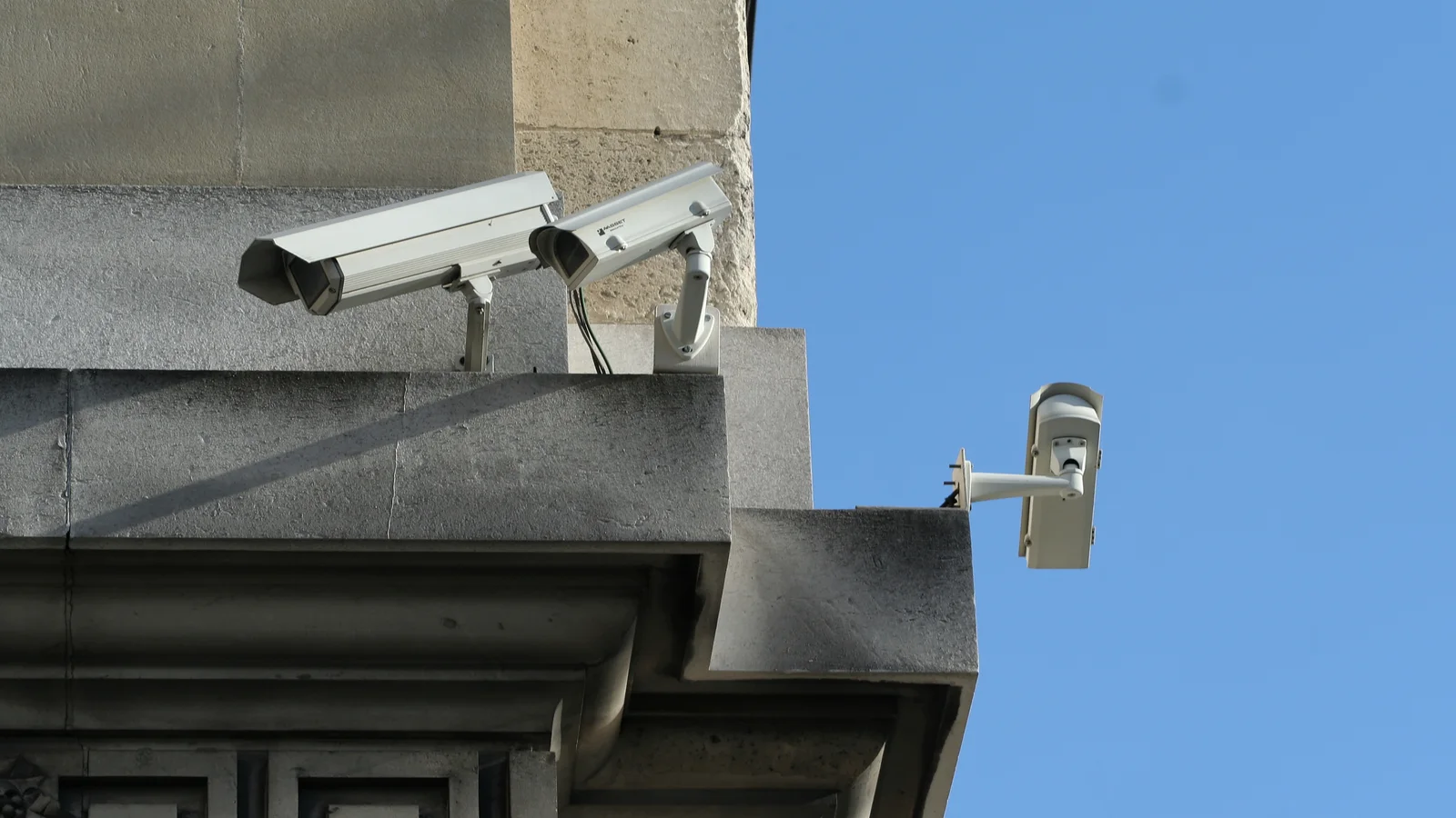Trois caméras de vidéosurveillance fixées sur une façade en pierre, quai des Orfèvres à Paris.